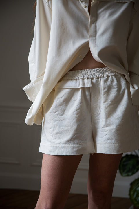 Lena is wearing White Canvas sustainable floral jacquard short shorts, size S. The short shorts have minimal modern aesthetics design allowing comfort and bringing self-confidence. This unique piece is made locally in Paris to reduce environmental impact and guarantee high quality and durability of the products.