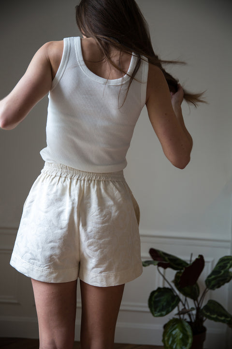 Lena is wearing White Canvas sustainable floral jacquard short shorts, size S. The short shorts have minimal modern aesthetics design allowing comfort and bringing self-confidence. This unique piece is made locally in Paris to reduce environmental impact and guarantee high quality and durability of the products.