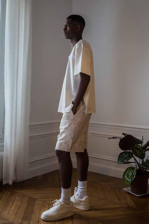 Thierno is wearing White Canvas sustainable natural cotton jersey oversized, genderless, seasonless t-shirt, one size. The natural cotton jersey t-shirt has minimal modern aesthetics design allowing comfort and bringing self-confidence. This unique piece is made locally in Paris to reduce environmental impact and guarantee high quality and durability of the products. 