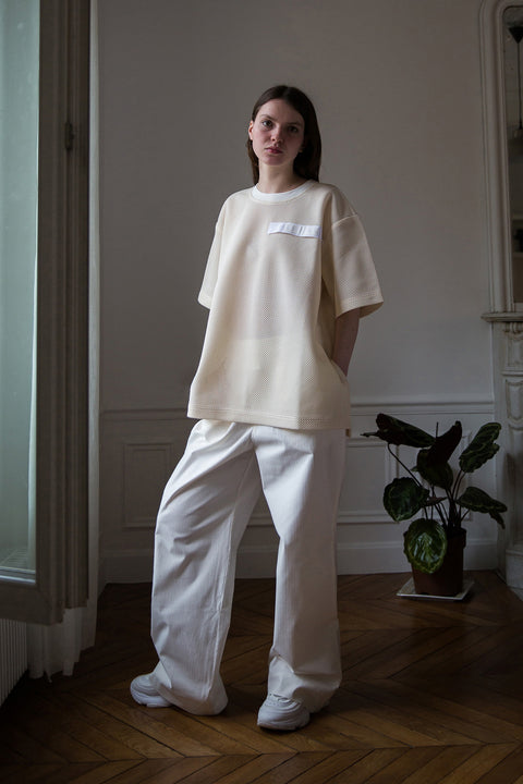 Dalva is wearing White Canvas sustainable mesh oversized, genderless, seasonless t-shirt, one size. The mesh t-shirt has minimal modern aesthetics design allowing comfort and bringing self-confidence. This unique piece is made locally in Paris to reduce environmental impact and guarantee high quality and durability of the products. 