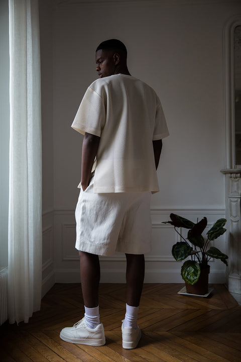Thierno is wearing White Canvas sustainable mesh oversized, genderless, seasonless t-shirt, one size. The mesh t-shirt has minimal modern aesthetics design allowing comfort and bringing self-confidence. This unique piece is made locally in Paris to reduce environmental impact and guarantee high quality and durability of the products. 