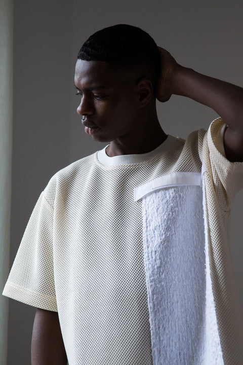 Thierno is wearing White Canvas sustainable mesh oversized, genderless, seasonless t-shirt, one size. The cotton stripes t-shirt has minimal modern aesthetics design allowing comfort and bringing self-confidence. This unique piece is made locally in Paris to reduce environmental impact and guarantee high quality and durability of the products. 